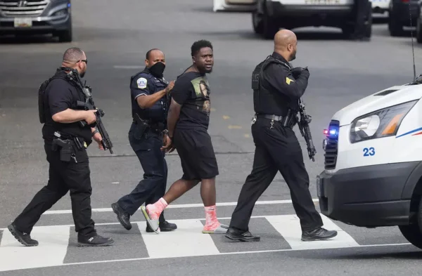 três policiais levam um homem negro algemado