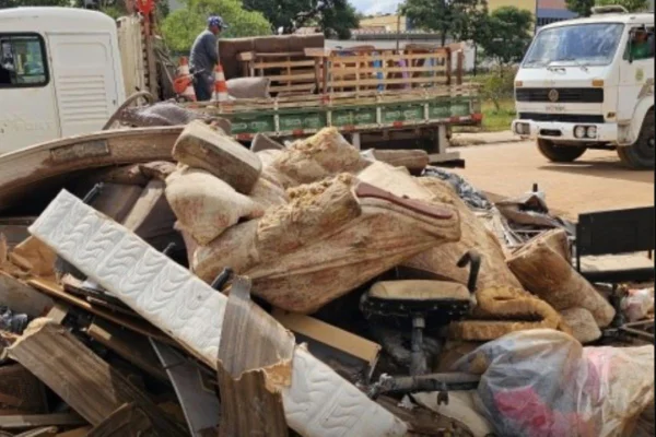 Imagens coloridas mostram um homem na carroceria de um caminhão, recolhendo entulho após chuvas em Santa Bárbara D´Oeste
