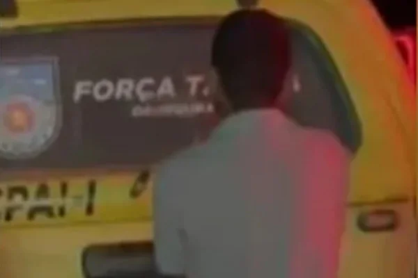 Imagem colorida de homem de costas com viatura da polícia ao fundo - Metrópoles