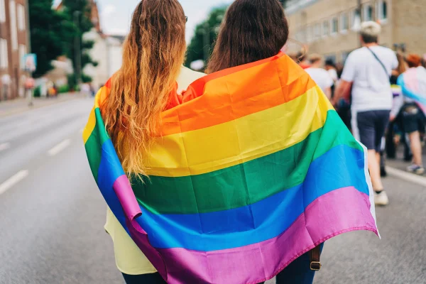 Foto colorida de duas pessoas com bandeira lgbt - Metrópoles
