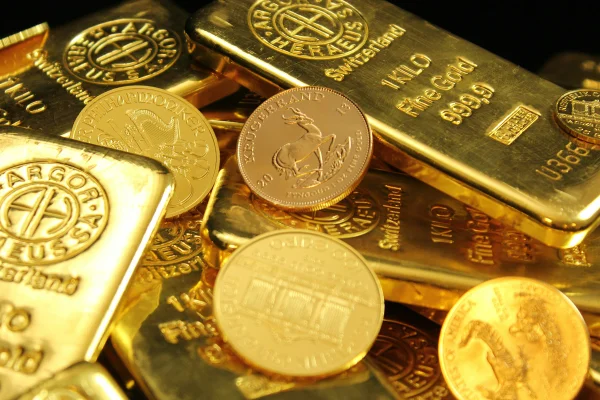 Foto colorida de moedas e tabletes de ouro - Metrópoles.
