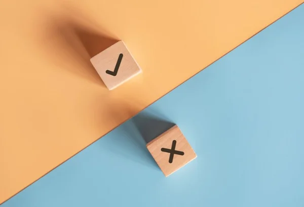 Dados com a letra x e um certo de cada lado do papel azul com laranja - Metrópoles