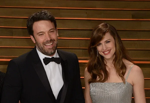 Jennifer Garner e Ben Affleck. Ele usa terno escuro e camiseta clara. Ela usa vestido prata- Metrópoles