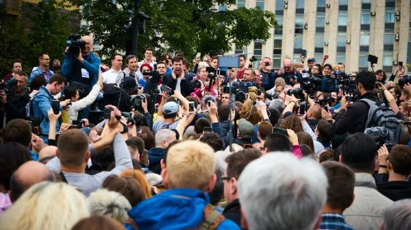Vários jornalistas e outras pessoas filmando um discurso no meio da rua