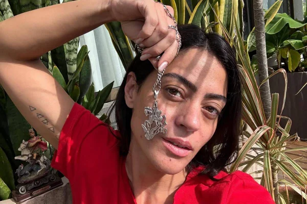 foto colorida do rosto de Carol Castro e da mão da atriz segurando medalha de são jorge - metrópoles