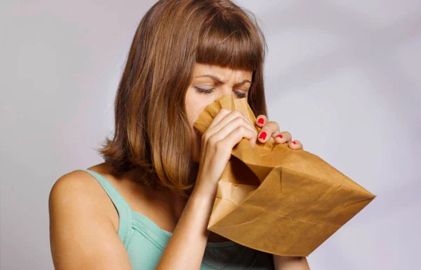Mulher tentando se acalmar respirando dentro de saco de pão
