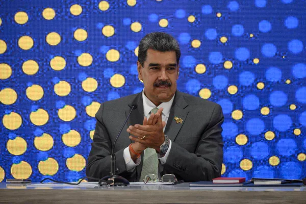 foto colorida de Nicolás Maduro sentado, de terno batendo palmas - metrópoles