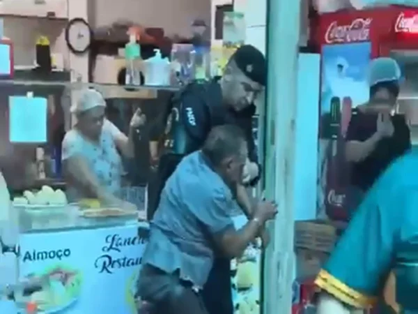 Policial prendendo homem suspeito de tenta matar ex-mulher a facadas em feira do Gama