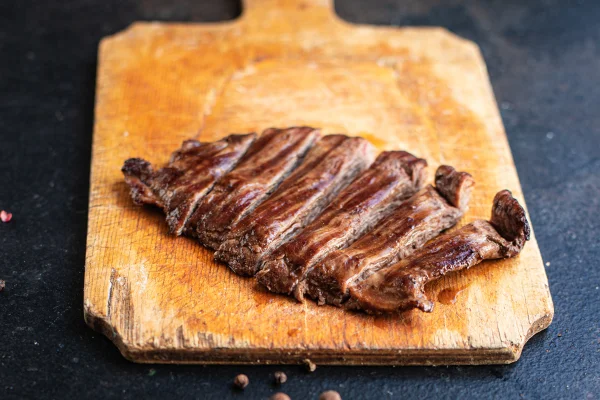 Foto colorida de carne cortada sob tábua de madeira - Malpassada, ao ponto ou bem-passada: qual o ponto certo da carne? - Metrópoles