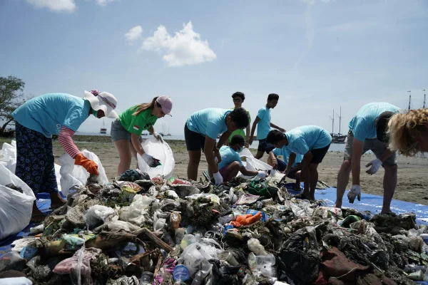 Fotografia colorida mostrando catadores em praia recolhendo o lixo-Metrópoles