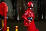 Charlene Davies usa capacete vermelho da TAG Heuer, jaqueta de couro e vestido de gala inspirado na F1 durante o Australian Fashion Week de 2025