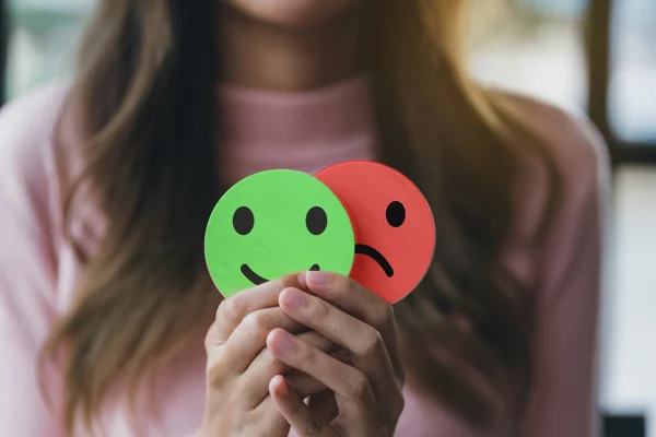 Foto de Mãos de mulher segurando rosto triste escondendo ou atrás de rosto sorridente feliz, bipolar e depressão, conceito de saúde mental - Metrópoles