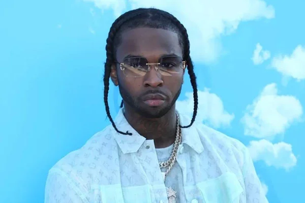 Foto colorida do rapper Pop Smoke de camisa branca em fundo azul - Metrópoles