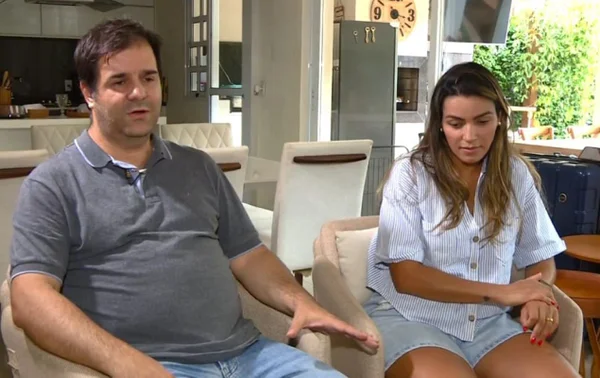 Imagem colorida de homem de camisa escura e mulher de camisa branca sentados concedendo entrevista - Metrópoles
