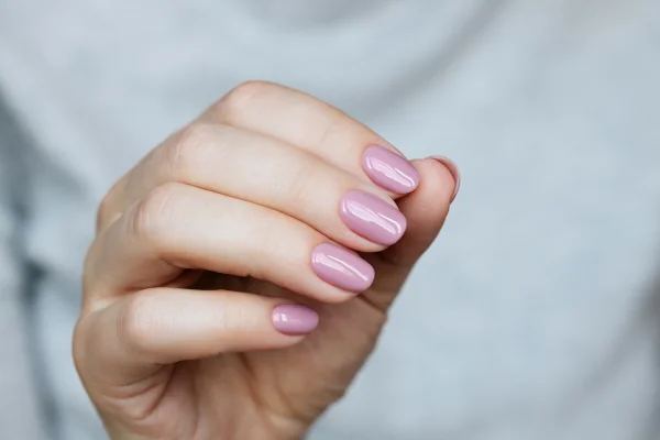 Mão feminina pintada no estilo princess nails, com esmalte rosa claro