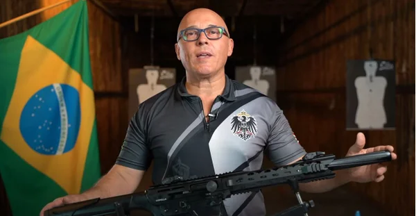 Otto Vieira, bolsonarista e empresário de Santa Catarina investigado por patrocinar atos golpistas. Ele segura uma metralhadora, em estande de tiro, com bandeira do Brasil atrás - Metrópoles