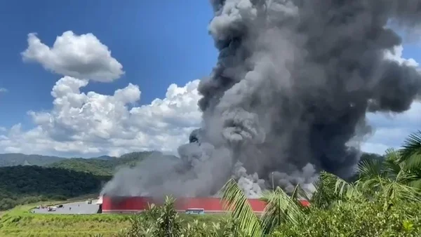 Imagem mostra incêndio num galpão em Brusque. Fumaça escura sai do local