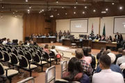Paulo Cupertino, sentado de camisa azul e cabeça baixa na frente de 3 policiais durante julgamento em 2024