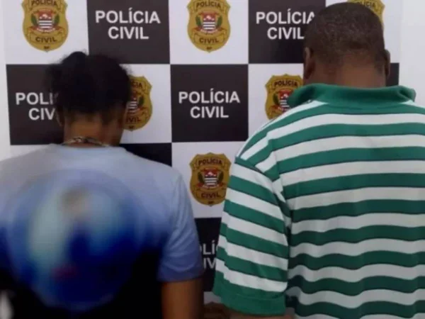 Mãe e padastro são presos no interior de São Paulo por torturar filhos. Na foto, eles aparecem de costas e virados pro painel da Polícia Civil - Metrópoles