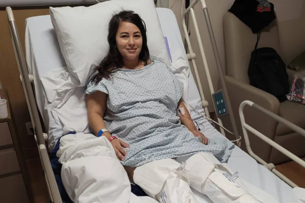 Foto colorida de mulher com as pernas cobertas em maca hospitalar - Metrópoles
