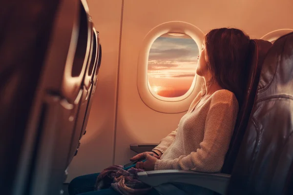 Mulher sentada em avião olhando para a janela - Metrópoles