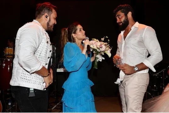 Amanda Vasconcelos tem um buquê de casamento nas mãos enquanto fala com o marido Henrique, que quer uma festa de casamento