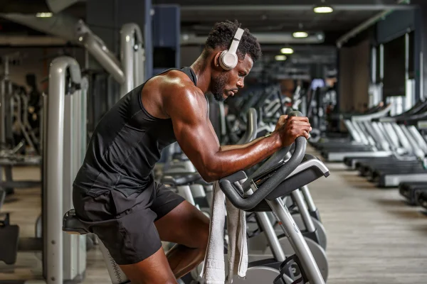 Imagem colorida mostra homem negro com roupas pretas fazendo cardio escutando música - Metrópoles