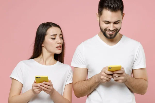 casal de blusa branca mexendo no celular