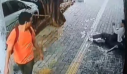 Homem de camiseta laranja olha para idosa caída no chão - Metrópoles