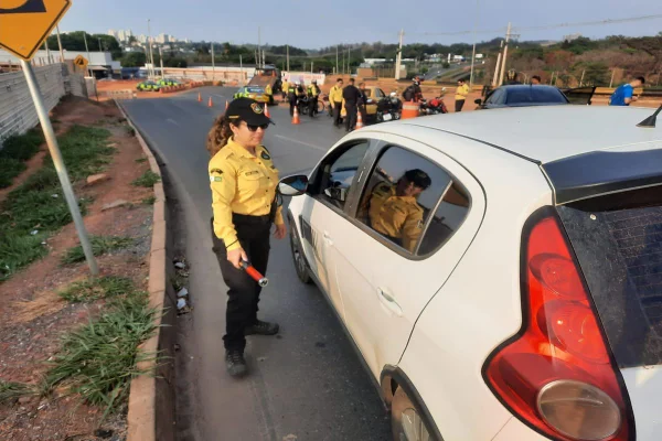 Foto de um carro branco e uma mulher de amarelo ao lado
