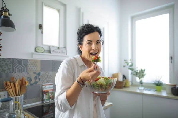 Mulher madura se alimentando na cozinha - Metrópoles