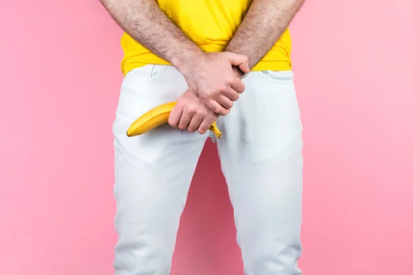 homem de blusa amarela segurando uma banana