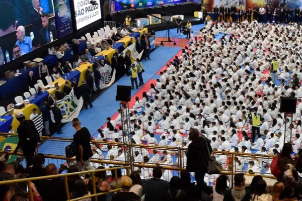 Imagem colorida mostra grupo de pessoas com kimono de karatê em evento em ginásio esportivo - Metrópoles