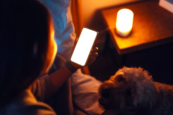 mulher mexendo no celular ao lado de cachorro