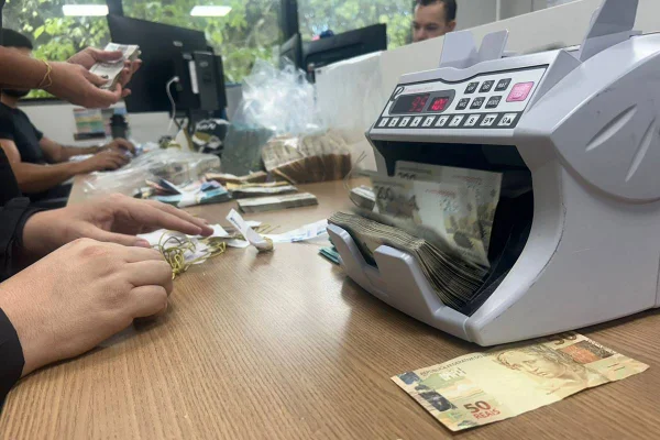 Homem conta dinheiro em máquina - Metrópoles