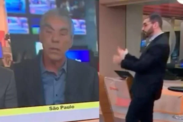 foto colorida e tremida de homem de terno falando com outro homem de terno que aparece em telão - metrópoles