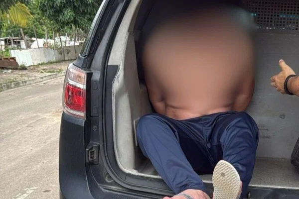 Imagens coloridas mostram jovem sem camisa preso em porta-malas de viatura - Metrópoles