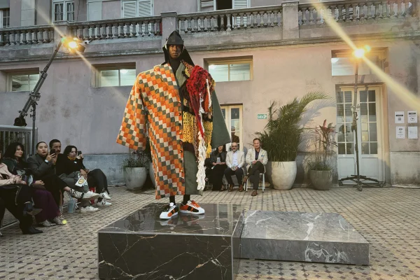Modelo usa look colorido com retalhos e tricô, em cima de uma base de pedra, em desfile de moda - Metrópoles