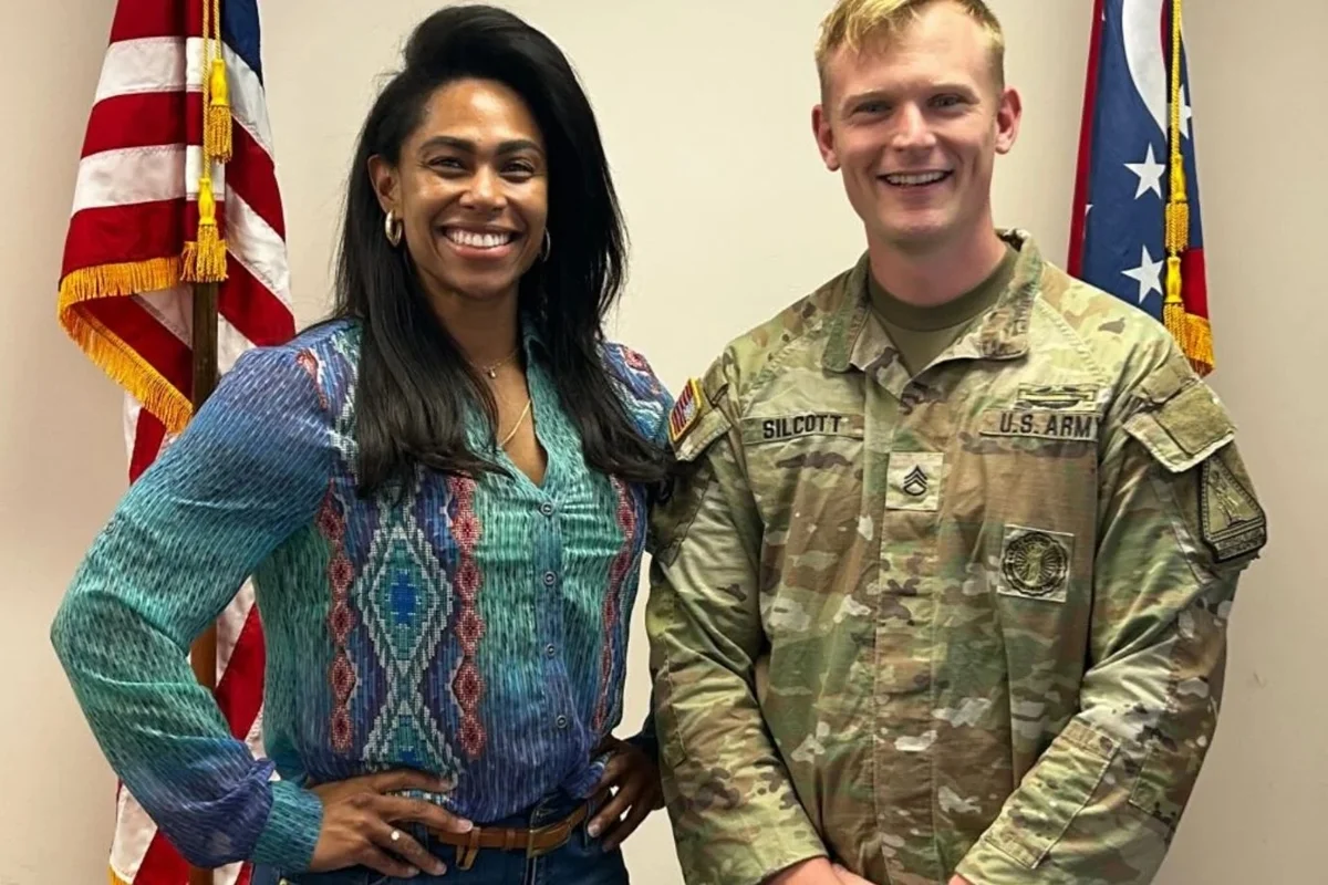 A jornalista Lise Oliveira sorrindo com trajes militares durante preparação na Guarda Nacional nos Estados Unidos.