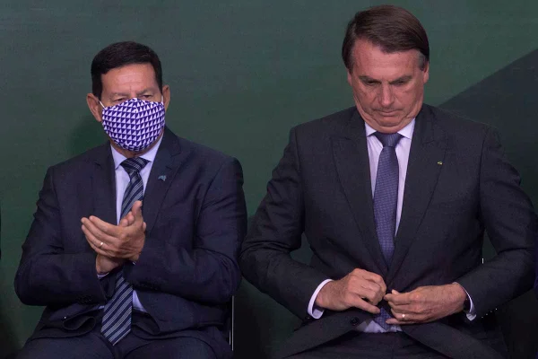 Presidente Bolsonaro abotoa o paleto e ao lado o Vice Presidente Hamilton Mourão aplaude algo no Palácio do Planalto - Metrópoles
