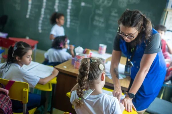 Foto colorida de sala de aula com estudantes com o aparelho