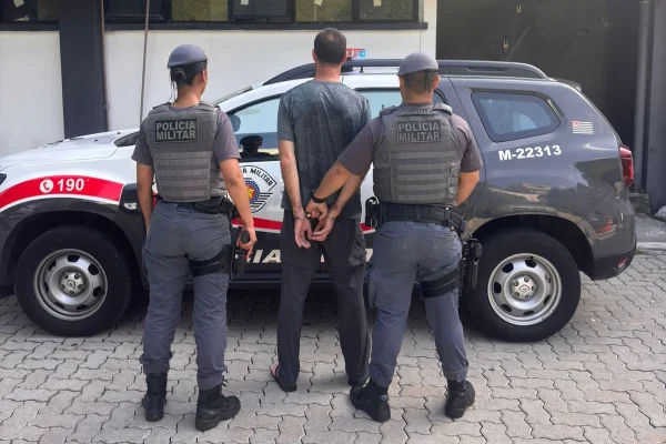 Policiais conduzem homem preso em frente a viatura - Metrópoles