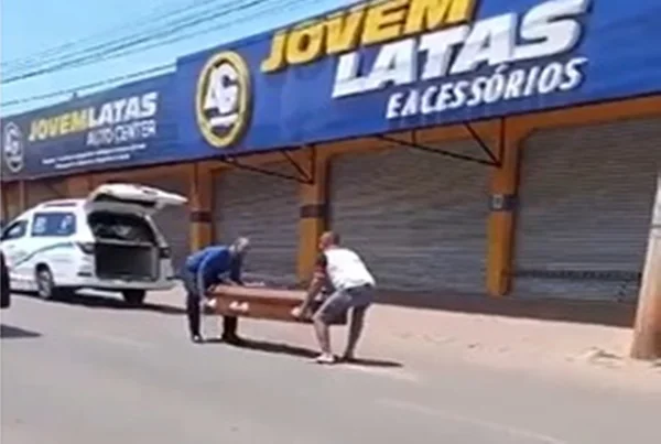Imagem colorida mostra duas pessoas carregando caixão