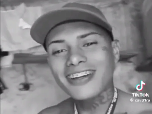 Imagem em preto e branco mostra Adelso sorrindo, sem camisa e de boné