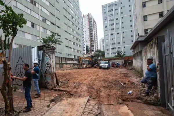 Foto colorida de terreno vazio, com prédios ao redor