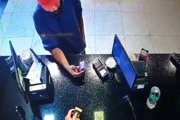 homem de casaco azul e boné vermelho passando cartão de crédito