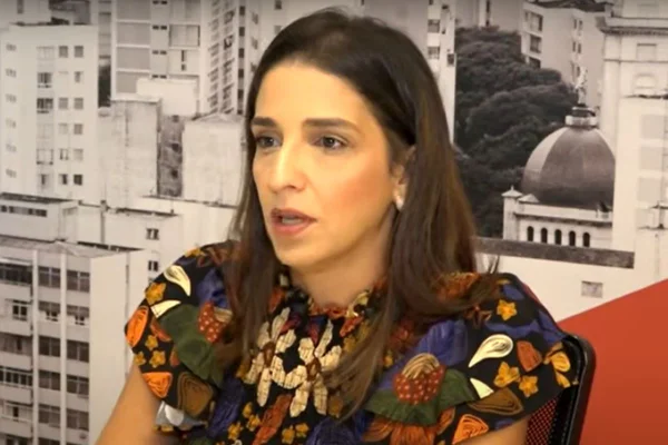 Mulher branca, de cabelos castanhos, fala durante entrevista
