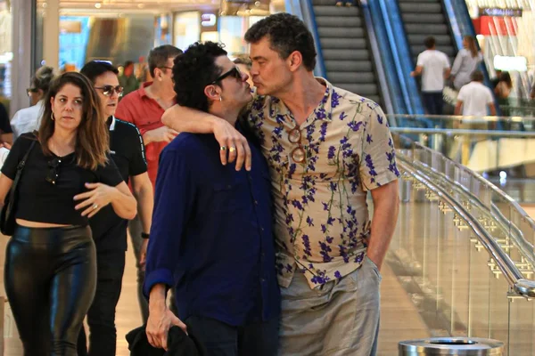Foto colorida de Carmo Dalla Vecchia. O ator está beijando um homem misterioso e está com uma roupa colorida - Metrópoles