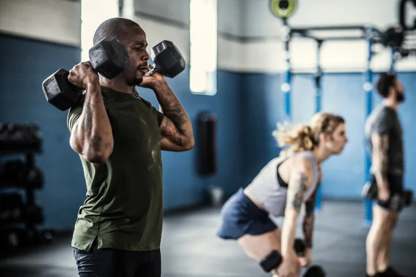 Homem realizando exercício físico com halteres em academia - Metrópoles