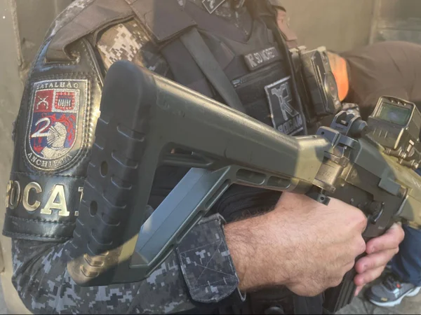 Imagem colorida mostra policial militar segurando arma. Ele é branco e veste uma farda. Metrópoles